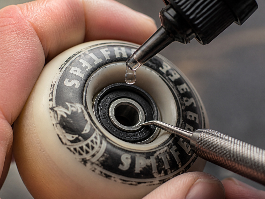 Adding a drop of lubricant to a skateboard bearing without removing it